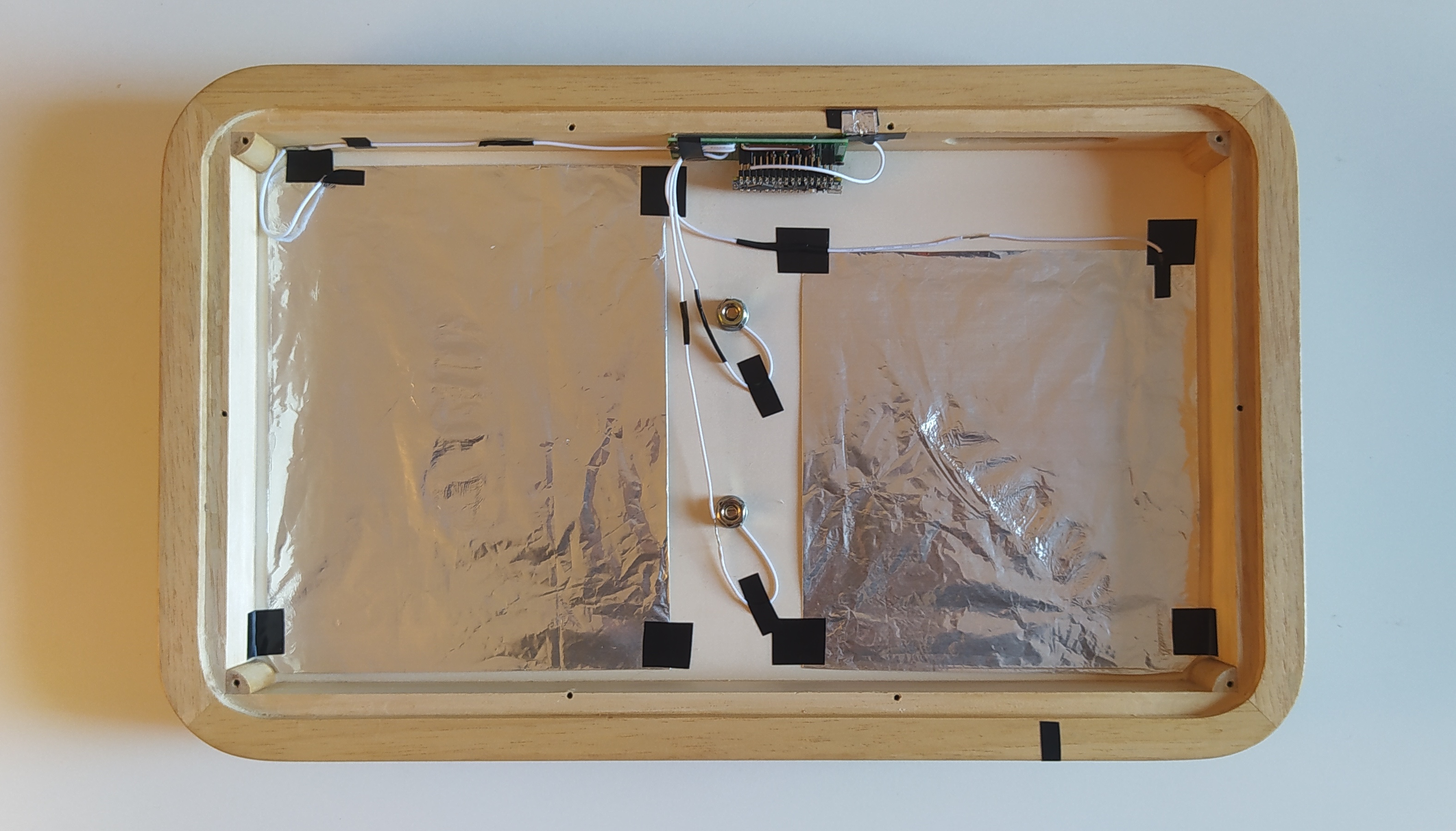 The insides of Surface: a
                  wooden box with sensors inside. A piezo pickup and
                  four capacitive sensors.